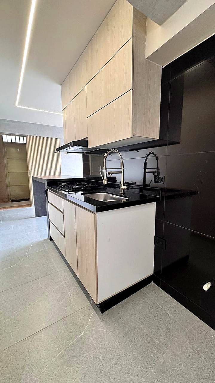 Cocina en madera clara y cubierta negra del apartamento en Rosales