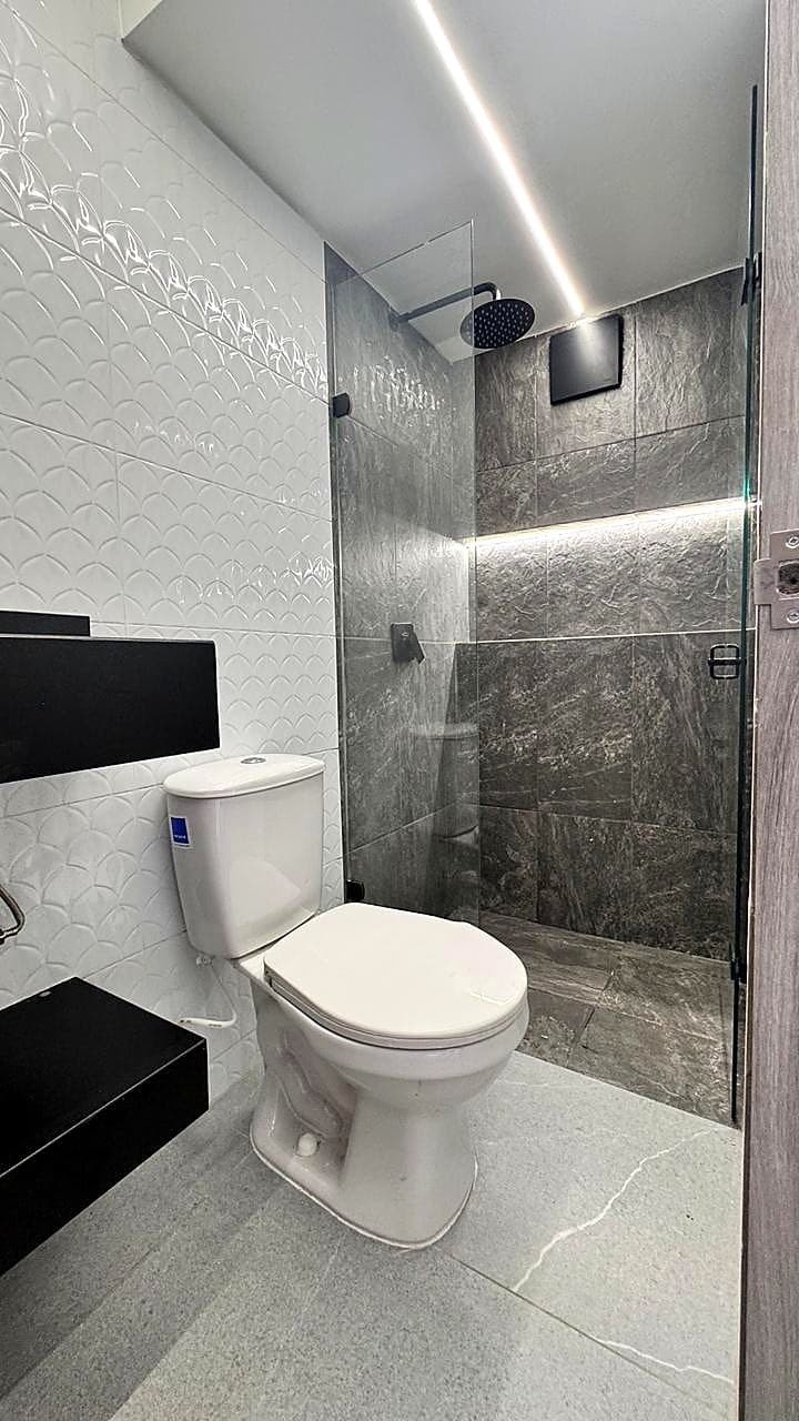 Baño con ducha en porcelanato gris y mampara de vidrio