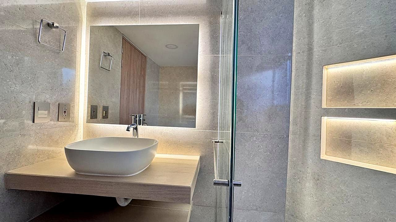 Baño en piedra con lavamanos de sobreponer y ducha de vidrio