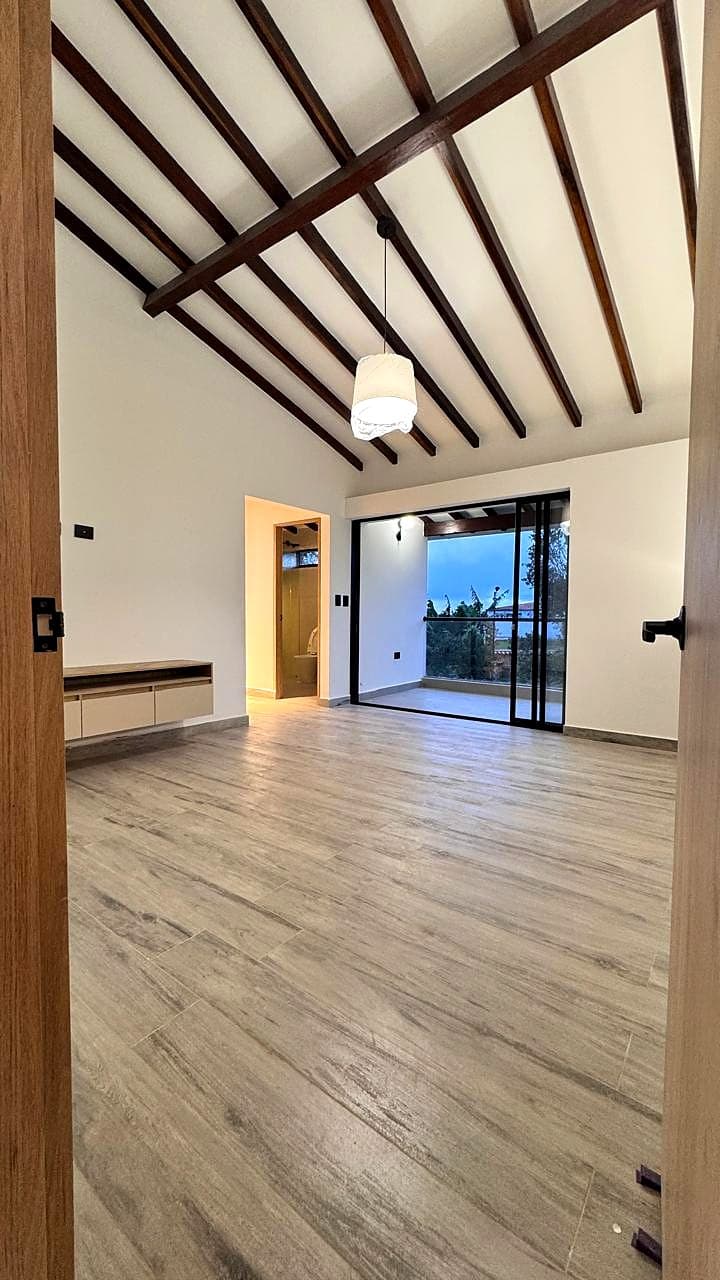 Sala con vigas de madera y carpintería negra en Arcoíris Acuarela