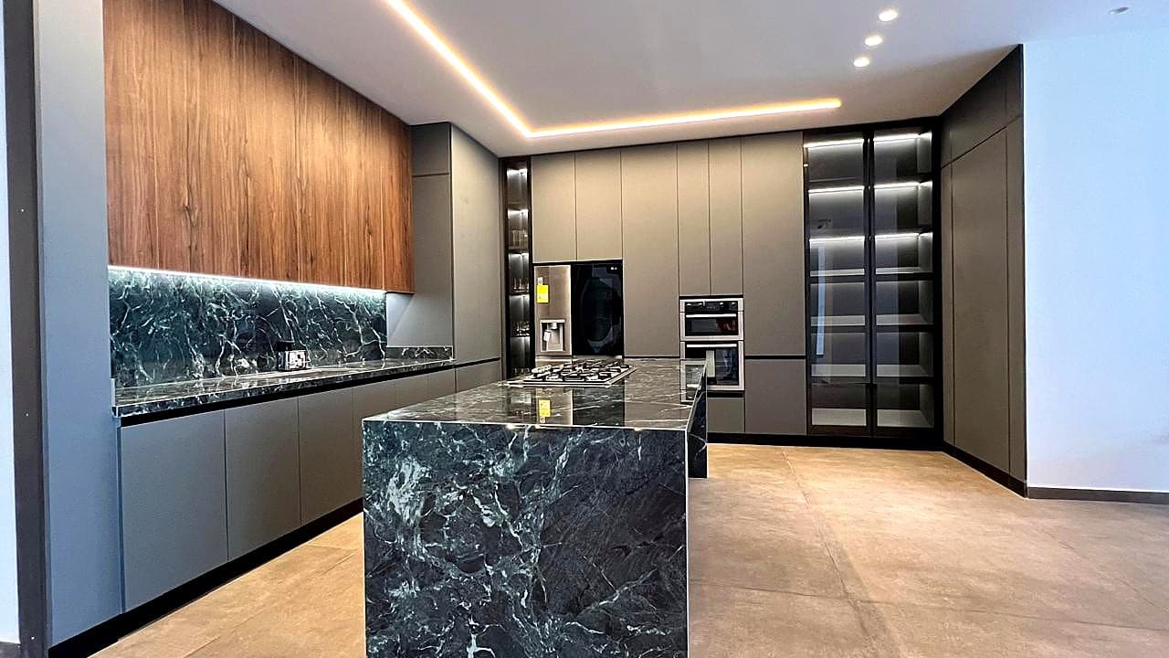 Cocina integrada con isla de piedra y muebles grises